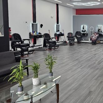 The floor at Legacy Barbershop & Lounge — barber stations and lounge seating with the glass table